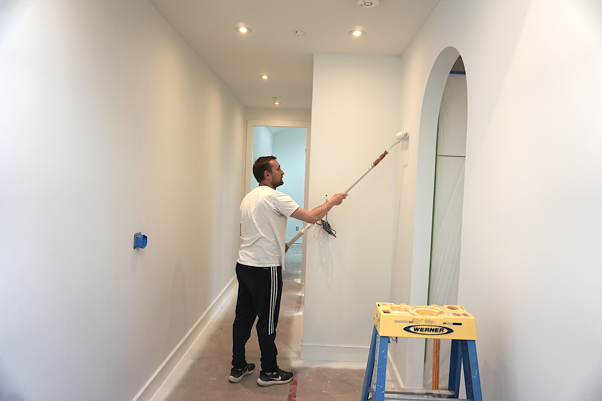 Professional painter applying a fresh coat of paint to a home's exterior wall, showcasing precise brushwork and smooth application. Blue World Painting ensures high-quality, durable finishes for residential painting projects.